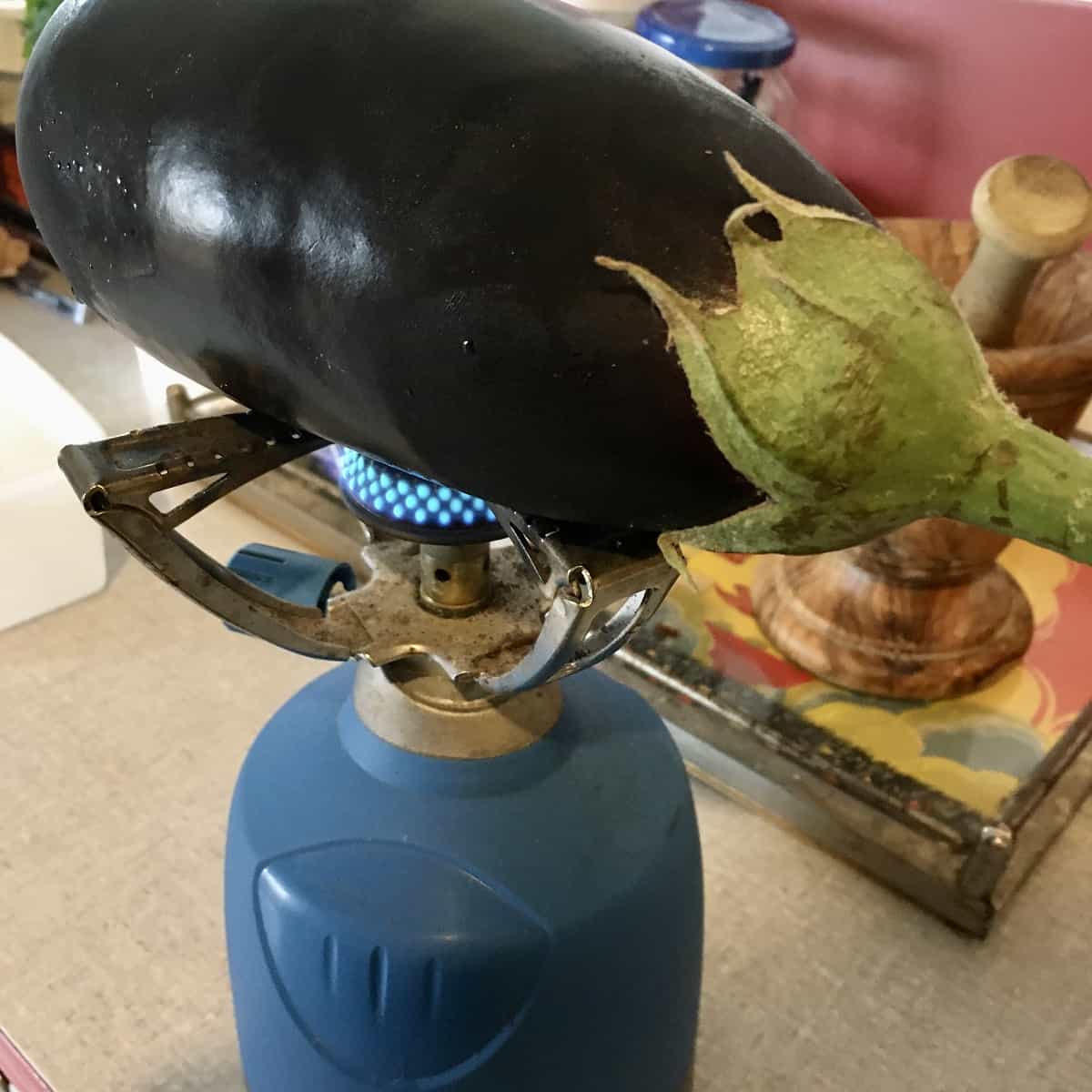 grilling an aubergine above open flame